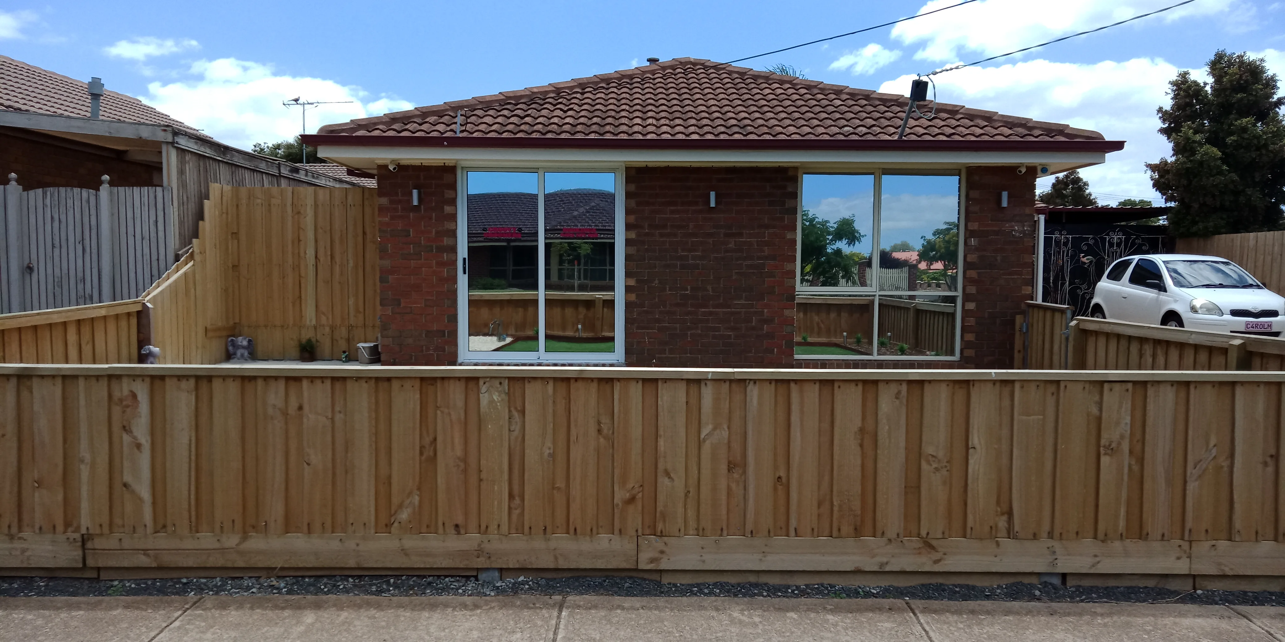 Street view of the Groovy Groomers premises &mdash; brick single-storey behind a timber fence, white car in the driveway